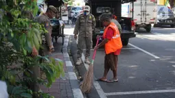 Petugas Satpol PP memberikan sanksi menyapu kepada warga yang tidak menggunakan masker di kawasan Pasar Baru, Jakarta, Jumat (21/8/2020). Sanksi tersebut dilakukan sebagai bagian dari upaya pencehagan penyebaran virus covid-19. (Liputan6.com/Immanuel Antonius)