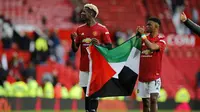 Gelandang MU, Paul Pogba dan Amad Diallo mengibarkan bendera Palestina usai ditahan imbang Fulham pada pekan ke-37 Liga Inggris di Stadion Old Trafford, Rabu (19/5/2021) dinihari WIB. Laga yang digelar di Stadion Old Trafford itu dihadiri sekitar 10 ribu penonton. (PHIL NOBLE/POOL/AFP)