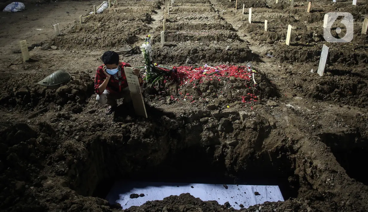 Seorang pria mengumandangkan adzan saat pemakaman dengan protokol covid-19 di TPU Rorotan, Jakarta, Rabu (14/7/2021). Data pasien meninggal per 14 Juli 2021 sebanyak 991 orang sehingga total akumulatif ada 69.210 orang yang meninggal dunia akibat corona di Indonesia. (Liputan6.com/Johan Tallo)