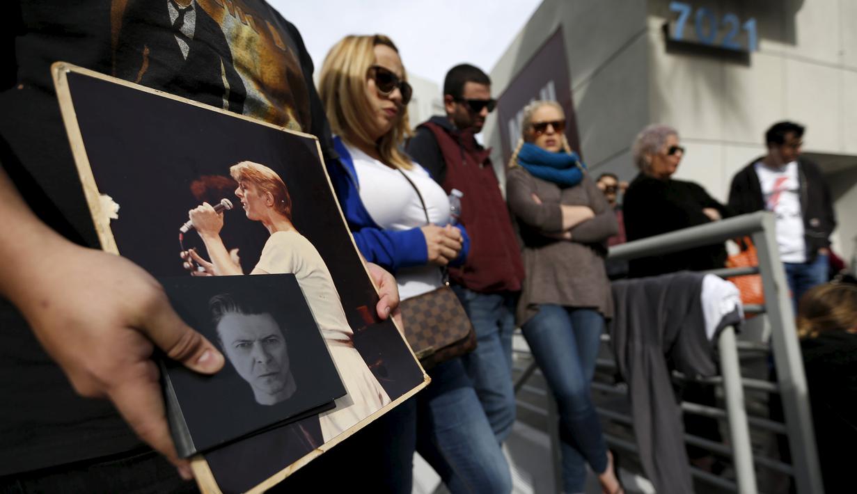 Penggemar membawa foto David Bowie  saat berkumpul di dekat bintang atas nama penyanyi legendaris itu di Hollywood Walk of Fame di Los Angeles, Senin (11/1). Bowie meninggal di usia 69 tahun dan baru saja merilis album ke-25 nya. (REUTERS/ Mario Anzuoni)
