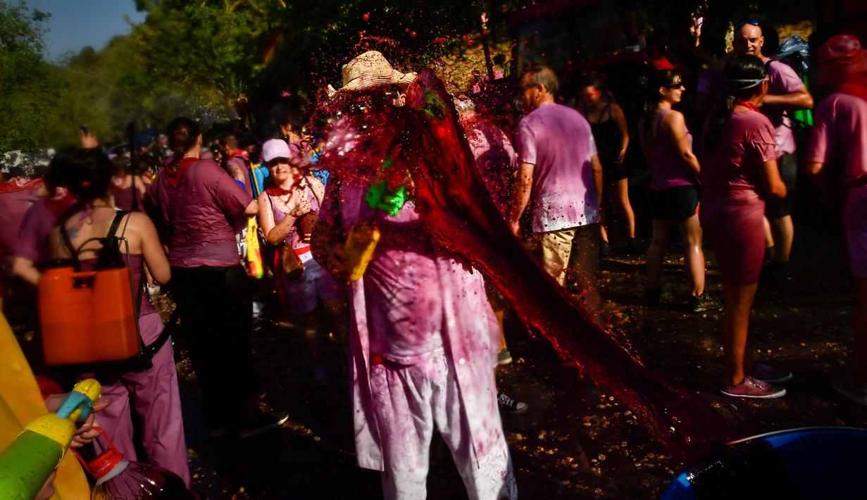 Peserta diguyur anggur merah saat ambil bagian dalam perang anggur di Haro, Spanyol utara, Sabtu (29/6/2019). Setiap peserta wajib mengenakan pakaian putih pada festival yang diselenggarakan rutin setiap bulan Juni di kota Haro, yang terkenal sebagai produsen anggur tersebut. (AP/Alvaro Barrientos)