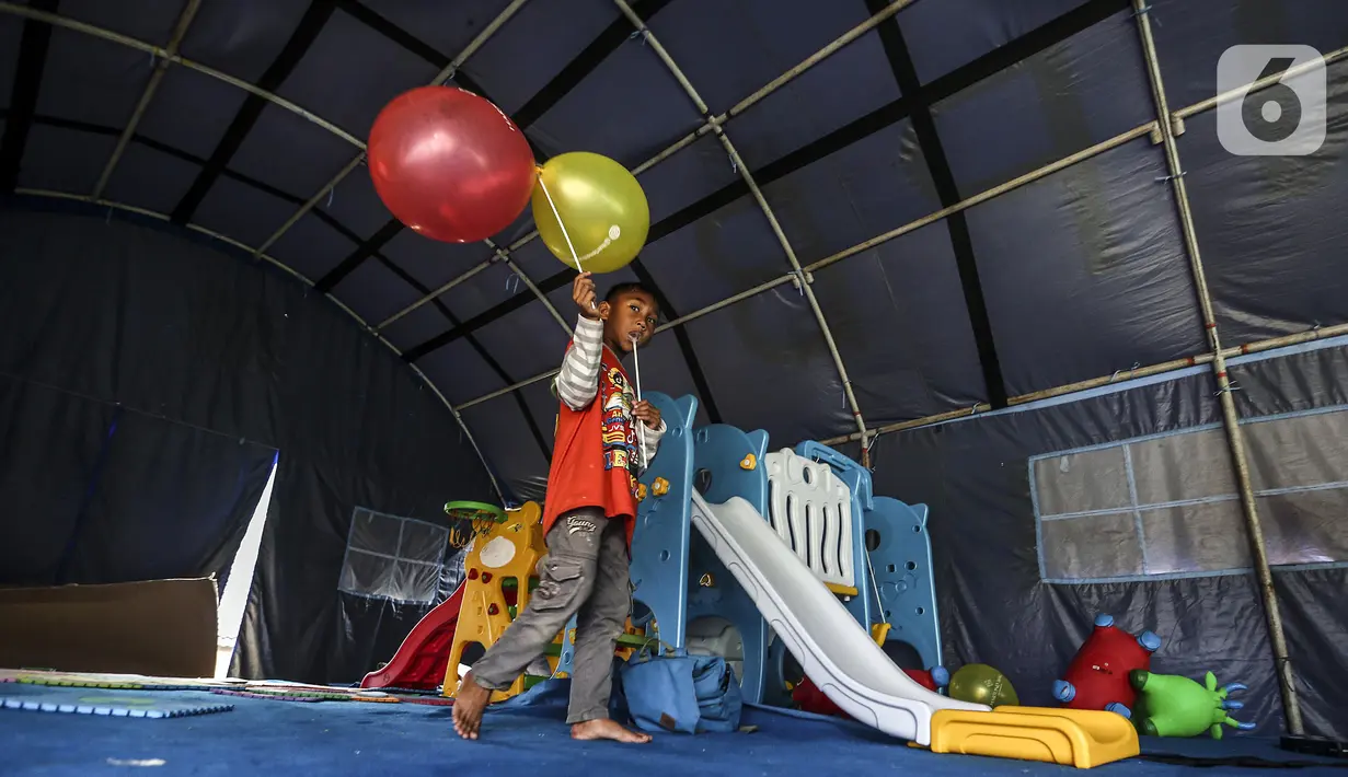Anak-anak pengungsi Gunung Merapi bermain balon di Barak Pengungsian Glagaharjo, Cangkringan, Sleman, Yogyakarta, Jumat (20/11/2020). Para relawan menyediakan berbagaai fasilitas bermain seperti puzle, kuda-kudaan, ayunan hingga prosotan. (Liputan6.com/Johan Tallo)