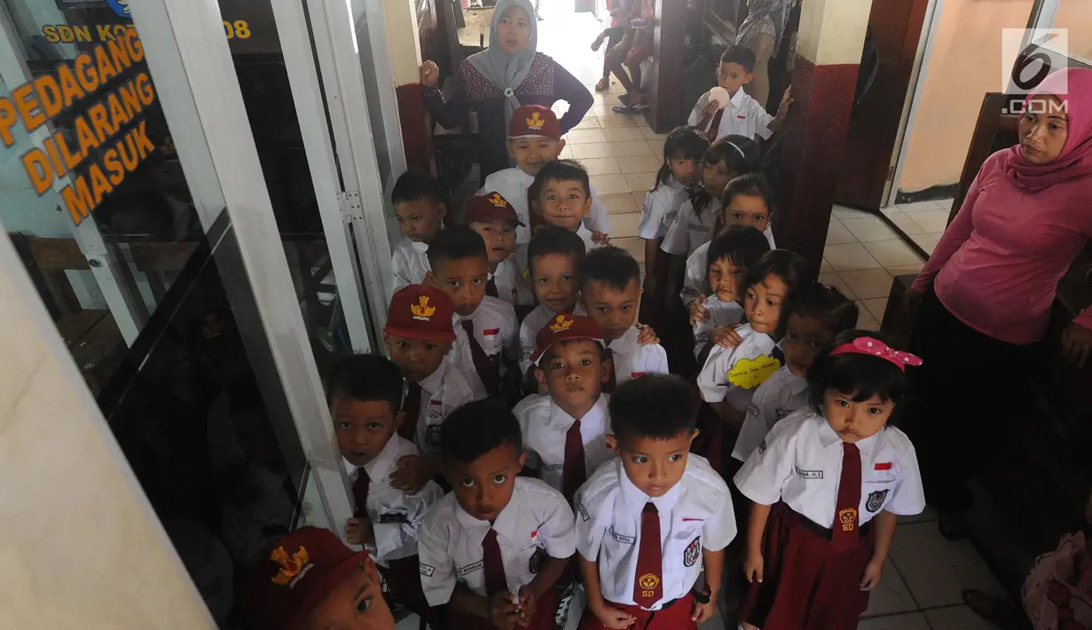 Siswa kelas 1 menunggu giliran untuk belajar di ruang guru SD Negeri Kotabatu 08 Kecamatan Ciomas Kabupaten Bogor, Senin (23/7). Hal itu terpaksa dilakukan akibat ambruknya dua bangunan kelas di lingkungan SDN Kota Batu. (Merdeka.com/Arie Basuki)