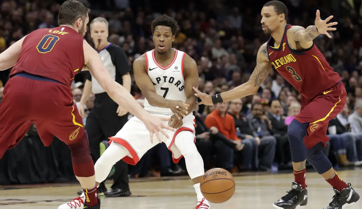 Pemain Toronto Raptors, Kyle Lowry (tengah) melakukan umpan melewati adangan dua pemain Cleveland Cavaliers pada lanjutan NBA basketball game di Quicken Loans Arena, (21/3/2018) Cleveland. Cavs menang 132-129. (AP/Tony Dejak)
