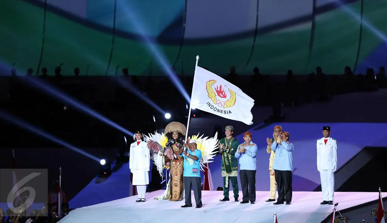 Gubernur Papua Lukas Enembe mengibarkan bendera PON sebagai penanda penyerahan estafet tuan rumah pada pesta penutupan PON XIX 2016 di Stadion Gelora Bandung Lautan Api, Kamis (29/9). (Liputan6.com/Helmi Fithriansyah)