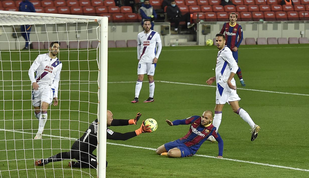 Kiper Eibar, Marko Dmitrovic (kiri) mementahkan tendangan striker Barcelona, Martin Braithwaite dalam laga lanjutan Liga Spanyol 2020/21 pekan ke-16 di Camp Nou, Selasa (29/12/2020). Eibar bermain imbang 1-1 dengan Barcelona. (AFP/Pau Barrena)