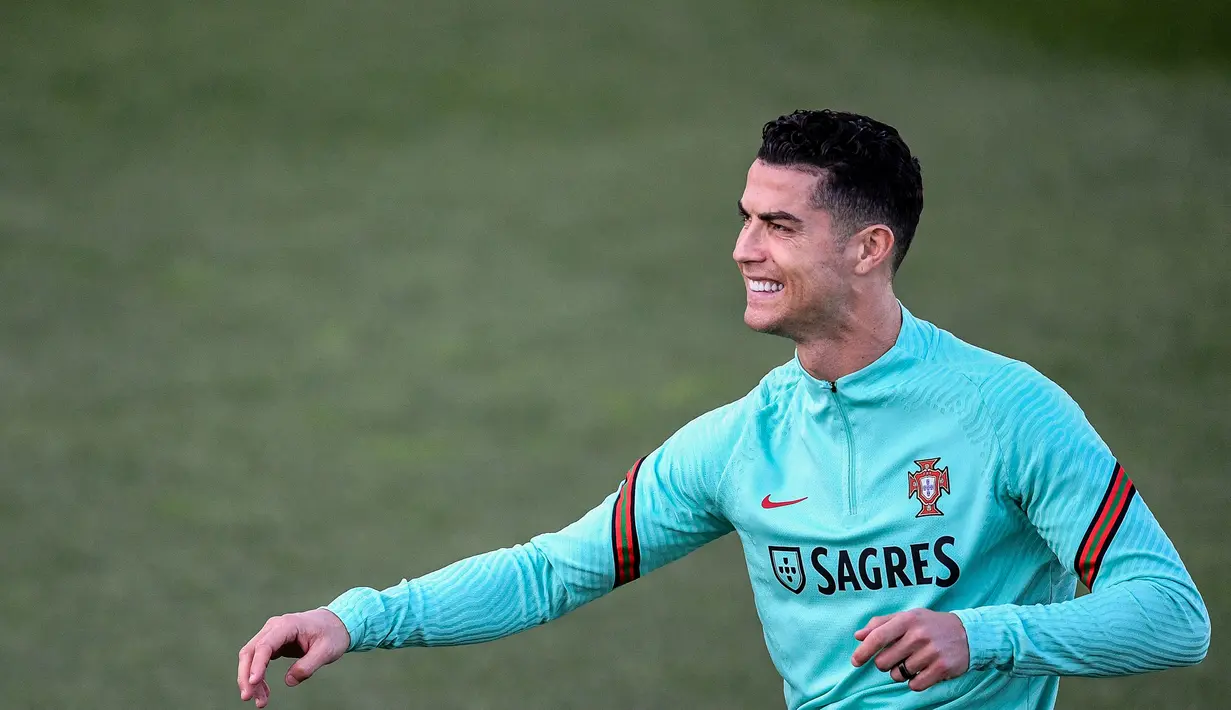 Pemain Portugal Cristiano Ronaldo tersenyum saat sesi latihan jelang menghadapi Turki pada pertandingan sepak bola kualifikasi Piala Dunia 2022 di kamp pelatihan Cidade do Futebol, Oeiras, Portugal, 21 Maret 2022. (PATRICIA DE MELO MOREIRA/AFP)