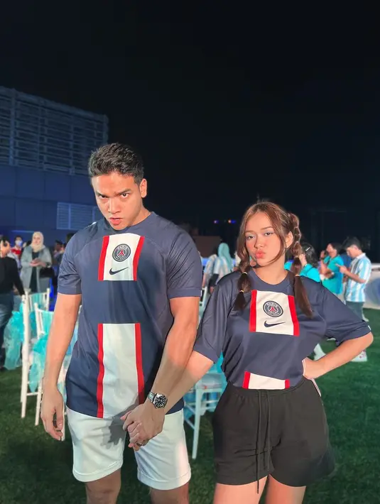 <p>Mengenakan atasan jersey yang sama, Fadly dan Rebecca terlihat mesra bergandengan. Fadly memadukan atasan jerseynya dengan celana pendek putih, sedangkan Rebecca memilih celana pendek berwarna hitam. Foto: Instagram.</p>