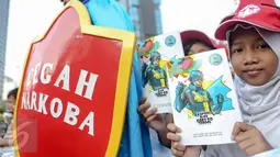 Sejumlah bocah memperlihatkan komik Kapten BNN saat ikut aksi Hari Anak Nasional di Bundaran HI, Jakarta, Minggu (2/8/2015). Mereka mengajak anak-anak Indonesia untuk menjauhi narkoba. (Liputan6.com/Faizal Fanani)