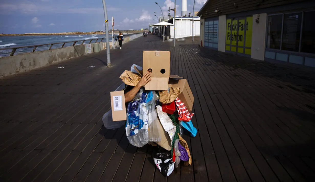 Seorang aktivis lingkungan berpakaian sampah kebanyakan dari plastik dalam unjuk rasa yang disebut Revolusi Mode di Tel Aviv, Israel, 19 November 2021. Aksi ini dilakukan untuk meningkatkan kesadaran iklim. (AP Photo/Oded Balilty)