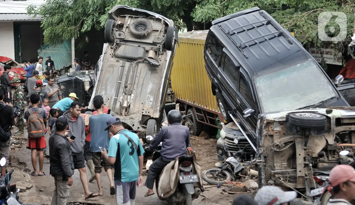 Warga melintasi sejumlah mobil yang terbalik akibat terjangan banjir di Perumahan Pondok Gede Permai, Jatiasih, Kota Bekasi, Jawa Barat, Kamis (2/1/2020). Derasnya terjangan banjir menyebabkan puluhan mobil terbalik dan belasan sepeda motor ringsek akibat terbawa arus. (merdeka.com/Iqbal Nugroho)