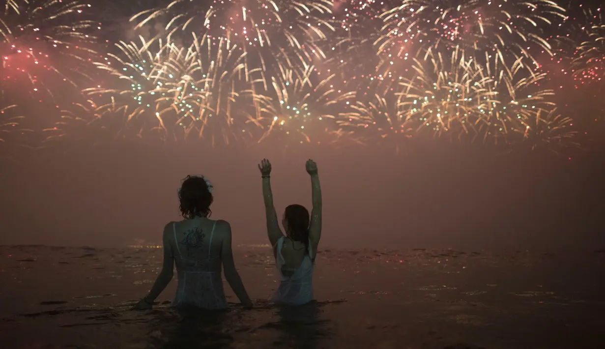 Warga menyaksikan pesta kembang api menyambut Tahun Baru 2019 di Pantai Copacabana, Rio de Janeiro, Brasil, Selasa (1/1). (AP Photo/Leo Correa)