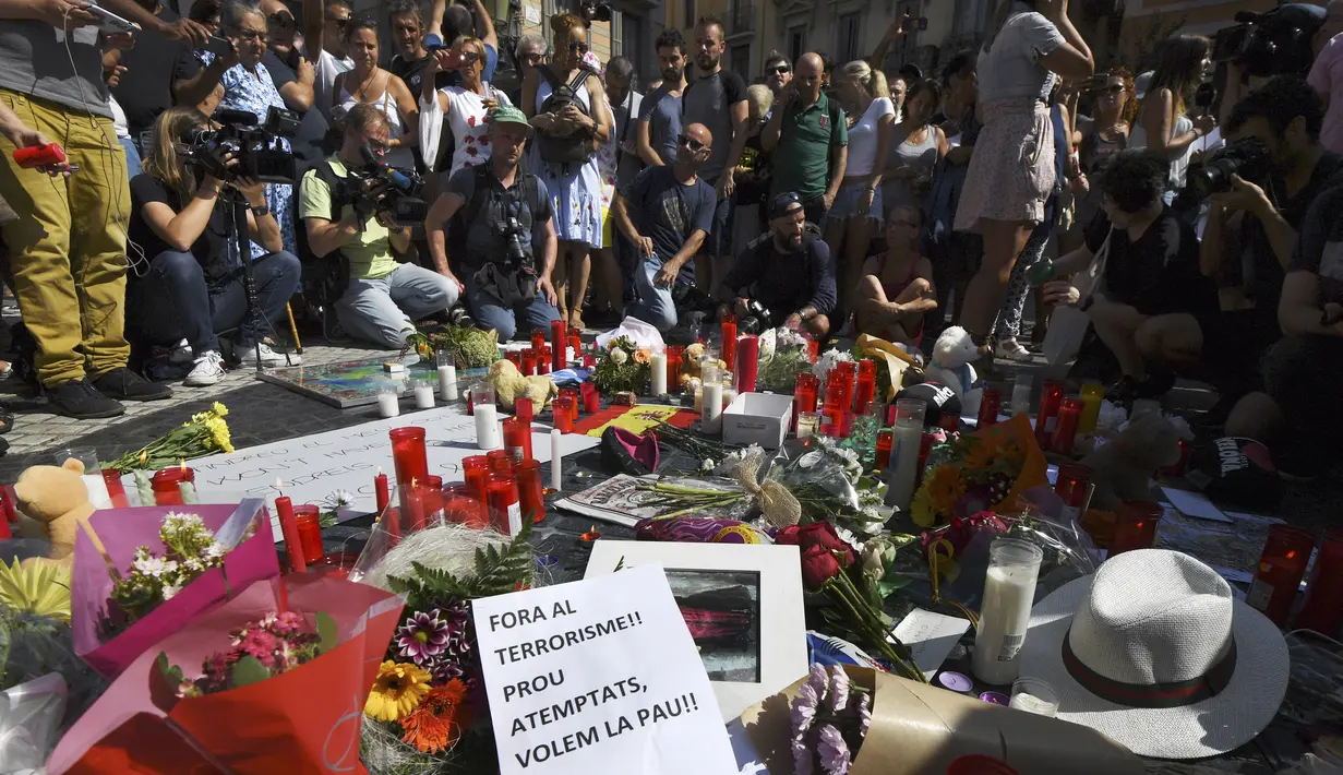 Orang-orang berkumpul sambil menaburkan bunga dan menyalakan lilin untuk memberi penghormatan kepada korban serangan Barcelona, Spanyol (18/8). Sebelum sebuah van menabrak kerumunan dan menawaskan 13 orang. (AFP Photo/Pascal Guyot)