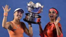 Martina Hingis (kiri) dan Sania Mirza berpose dengan trofi juara ganda putri setelah mengalahkan Lucie Hradecka dan Andrea Hlavackova di final tenis Australia Terbuka 2016 di Melbourne Park, Australia, (29/1/2016). (AFP/Peter Parks)