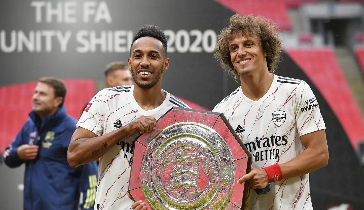 Penyerang Arsenal, Pierre-Emerick Aubameyang dan bek David Luiz berpose dengan trofi Community Shield usai pertandingan melawan Liverpool di stadion Wembley, London, Sabtu, (29/8/2020). Arsenal mengalahkan Liverpool 5-4 dalam adu penalti setelah pertandingan seri 1-1. (Justin Tallis/Pool via AP)