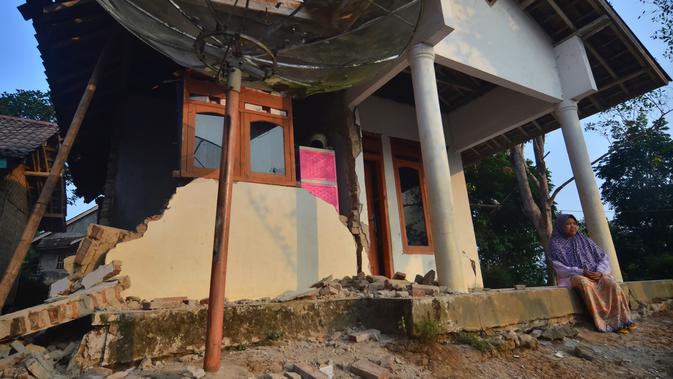 Warga duduk di rumah yang rusak usai gempa melanda Pandeglang, Banten, Sabtu (3/8/2019). Gempa Banten berpusat di kedalaman 48 kilometer Barat Daya Pandeglang. (RONALD SIAGIAN/AFP)