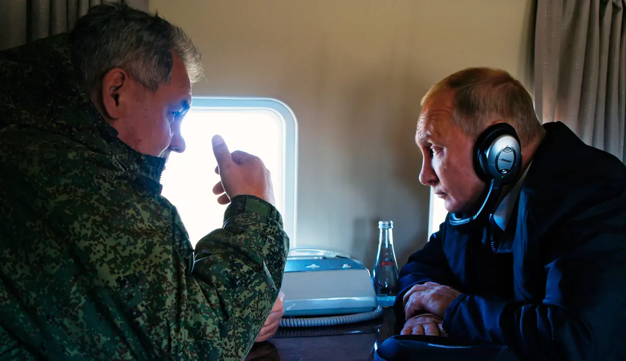 Presiden Rusia Vladimir Putin (kanan) mendengarkan Menteri Pertahanan Rusia Sergei Shoigu di jendela helikopter saat memantau latihan militer Vostok 2018 di Siberia Timur, Rusia, Kamis (13/9). (Alexei Nikolsky, Sputnik, Kremlin Pool Photo via AP)