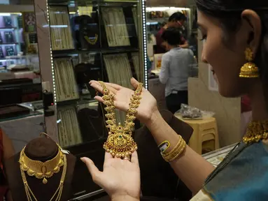 Seorang perempuan berbelanja perhiasan emas pada hari Akshay Tritiya yang dianggap menguntungkan untuk membeli emas di Mumbai, India, Selasa (3/5/2022). Membeli emas adalah kegiatan yang populer di Akshaya Tritiya, karena ini adalah simbol utama kekayaan dan kemakmuran. (AP Photo/Rajanish kakade)