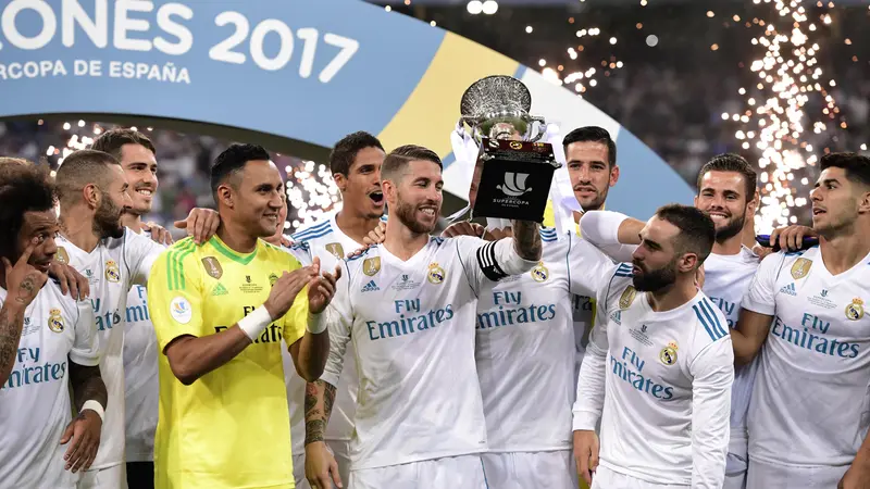 Bek Real Madrid, Sergio Ramos (tengah), mengangkat trofi Piala Super Spanyol 2017 usai mengalahkan Barcelona 2-0 pada leg kedua di Estadio Santiago Bernabeu, Kamis (17/8/2017) dini hari WIB. Real Madrid unggul agregat 5-1 (AFP/Javier Soariano)