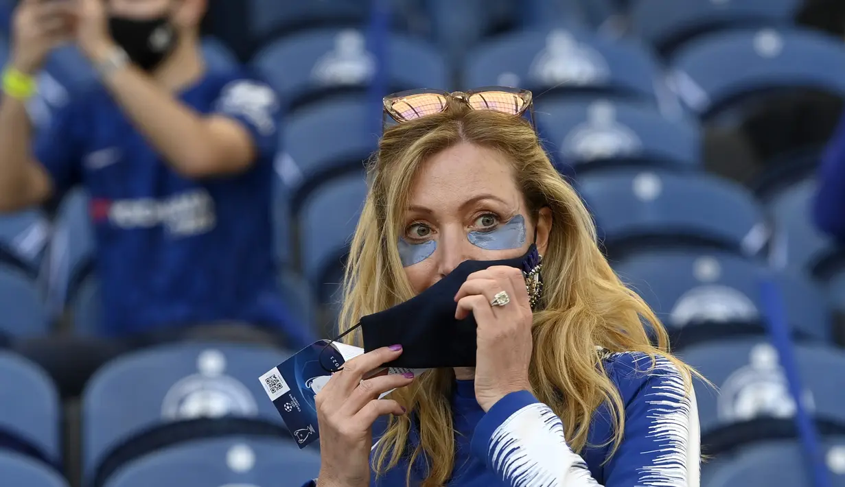 Seorang suporter wanita Chelsea menyesuaikan masker wajahnya di tribun sebelum dimulainya pertandingan final Liga Champions antara Manchester City dan Chelsea di Stadion Dragao di Porto, Portugal, Sabtu (29/5/2021). (Pierre Philippe Marcou / Pool via AP)