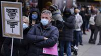 Orang-orang mengantre di tempat pengujian COVID-19 di Times Square, New York, Senin (13/12/2021). Wajib masker di semua tempat umum dalam ruangan di negara bagian New York mulai berlaku pada Senin ketika para pejabat menghadapi lonjakan kasus COVID-19 dan rawat inap. (AP Photo/Seth Wenig)