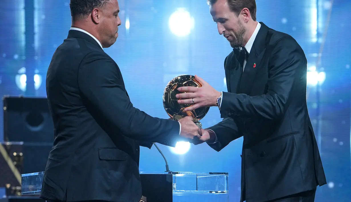 Pesepak bola Inggris, Harry Kane, menerima trofi penghargaan pemain terbaik dari mantan pesepak bola Brasil, Ronaldo Nazario, dalam acara penganugerahan Ballon d’Or di London Palladium Theatre, London, Inggris, Senin (26/10/2026). (AP Photo/Kin Cheung)