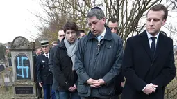 Presiden Prancis Emmanuel Macron melihat makam Yahudi yang dicoret simbol Nazi di pemakaman Yahudi, Quatzenheim, Prancis, Selasa (19/2). Macron menyatakan pelaku tidak layak menjadi warga Prancis. (Frederick FLORIN/AFP)