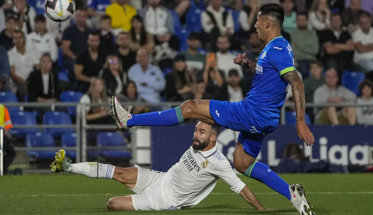 Bek Real Madrid Dani Carvajal berebut bola dengan bek Getafe Fabrizio Angileri pada pekan delapan La Liga musim 2022/2023 di Stadion Coliseum Alfonso Perez, Minggu (9/10/2022) dini hari WIB. Real Madrid menutup laga dengan kemenangan 1-0 dan untuk sementara duduk di posisi puncak dengan 21 poin. (AP Photo/Bernat Armangue)