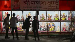 Orang-orang melihat patung dewa Hindu berkepala gajah Lord Ganesha yang dipajang di sebuah bengkel menjelang festival Ganesh Chaturthi di Mumbai (12/8/2021). Festival Ganesh Chaturthi adalah perayaan kelahiran Ganesha, dewa kebijaksanaan, kemakmuran, dan keberuntungan Hindu. (AFP/Punit Paranjpe)