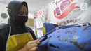 Perajin menyelesaikan proses pembuatan batik di  Batik Tradisiku, Bogor, Jawa Barat, Kamis (6/8/2020). Perajin batik mitra binaan Pertamina ini berinovasi dengan membuat motif dan warna baru untuk mengatasi anjloknya penjualan batik sebagai dampak ekonomi wabah corona. (merdeka.com/Arie Basuki)
