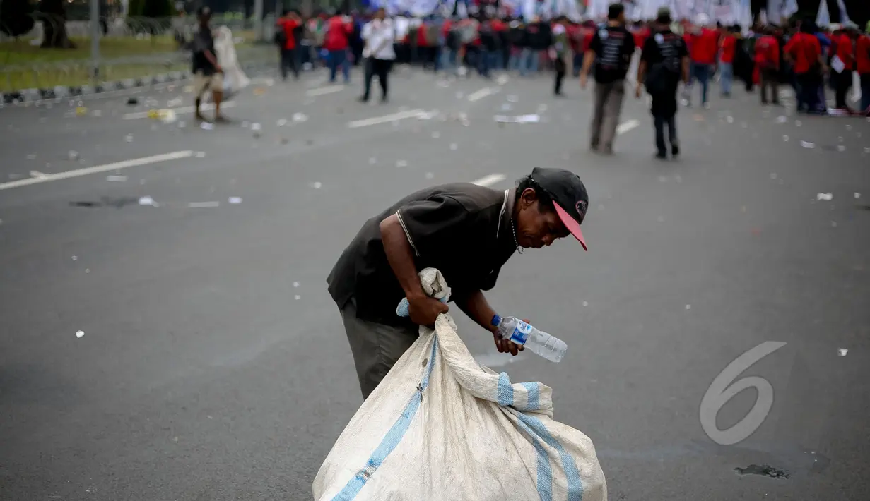 Pemulung memungut botol plastik saat peringatan hari buruh sedunia yang jatuh pada tanggal 1 Mei di depan Istana Merdeka, Jakarta, Jumat (1/5/2015). Aksi demo May Day menyisahkan sejumlah sampah berserakan di jalan. (Liputan6.com/Faizal Fanani)