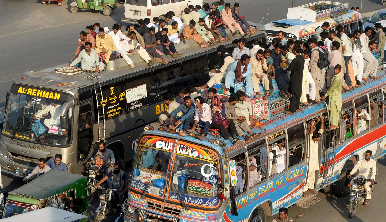 Sejumlah penumpang duduk di atas atap bus saat mudik menuju kampung halaman untuk merayakan Idul Adha di Lahore, Pakistan, Sabtu (10/8/2019). Umat Islam di seluruh dunia merayakan Idul Adha yang identik dengan tradisi berkurban. (Photo by ARIF ALI / AFP)