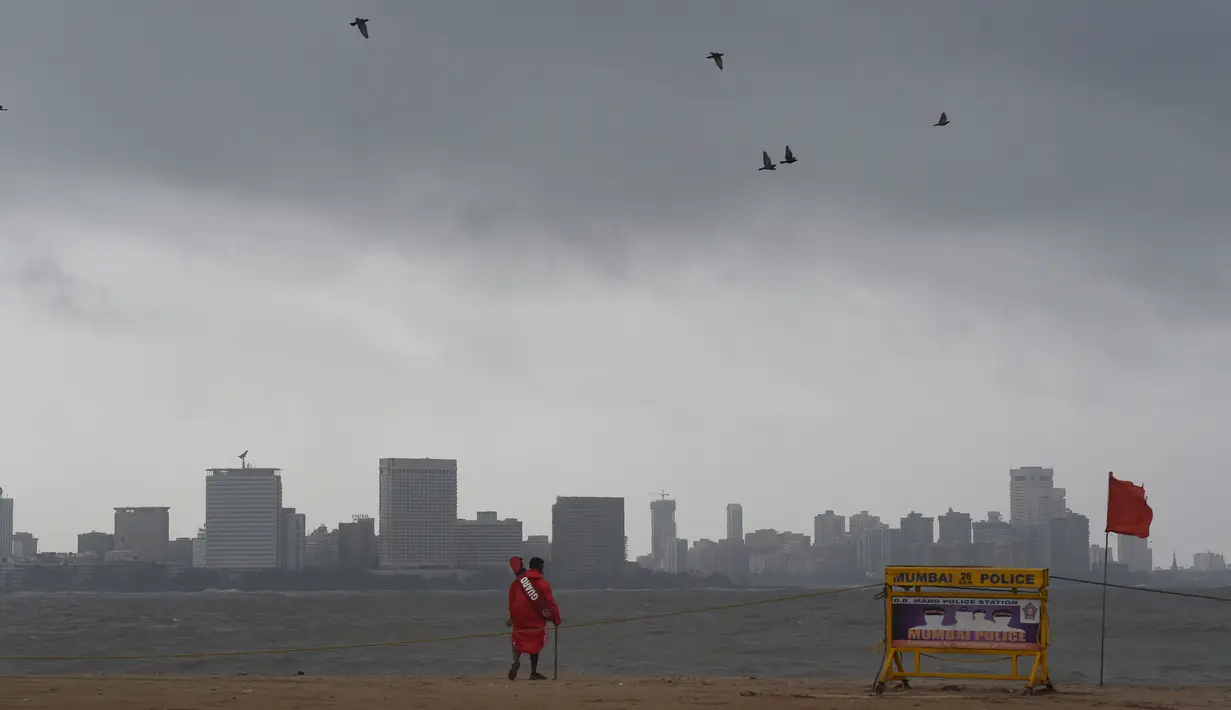 Penjaga pantai mengecek suasana pantai Girgaum Chowpatty setelah penutupannya saat awan gelap menyelimuti langit Mumbai (12/6/2019). Sebanyak hampir 300 ribu warga negara bagian Gujarat, India, akan dievakuasi menyusul adanya badai siklon Vayu. (AFP Photo/Punit Paranjpe)