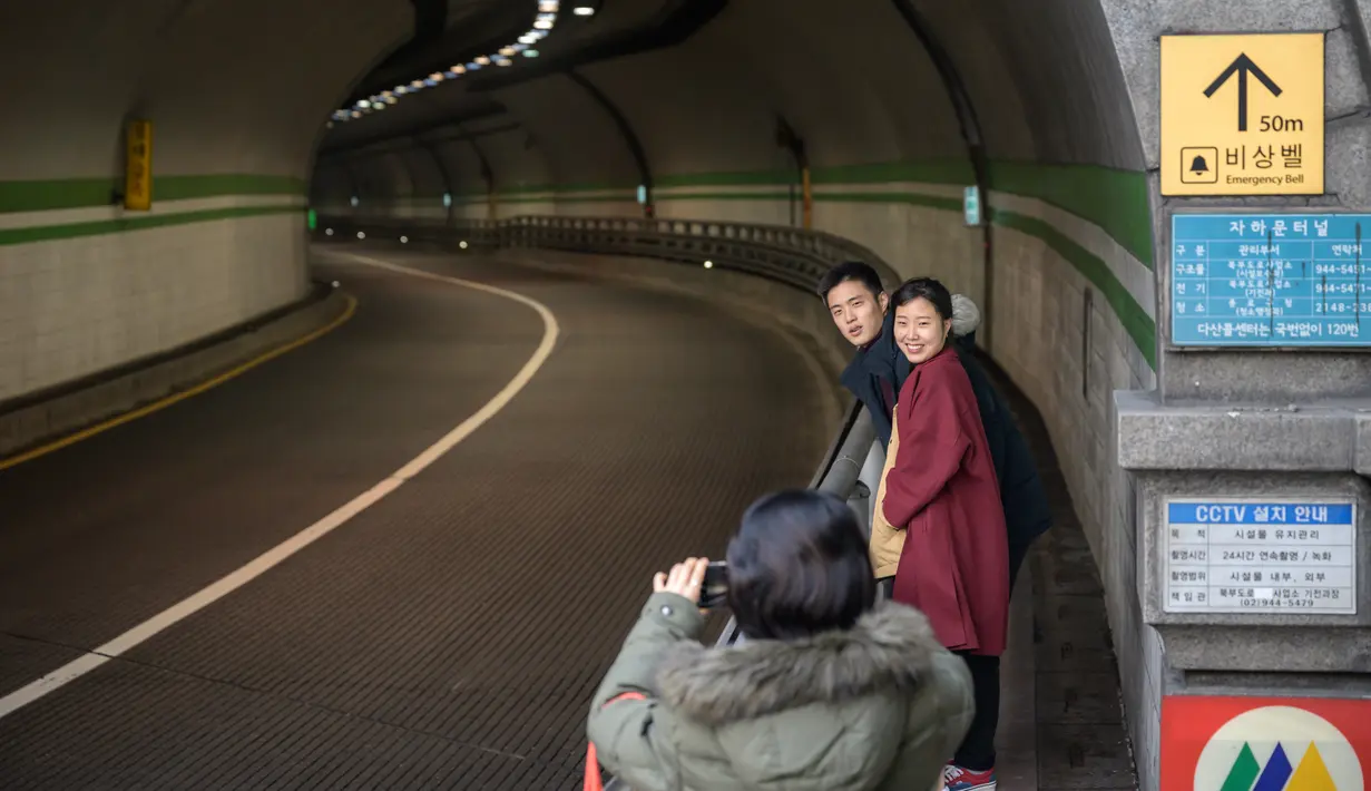Pasangan berpose untuk foto di sebuah terowongan yang ditampilkan dalam film berjudul 'Parasite', di Seoul pada 13 Februari 2020. Lokasi syuting Parasite di Korea Selatan semakin ramai dikunjungi turis setelah film tersebut berhasil memboyong dan mendominasi di penghargaan Oscar 2020. (Ed JONES/AFP)