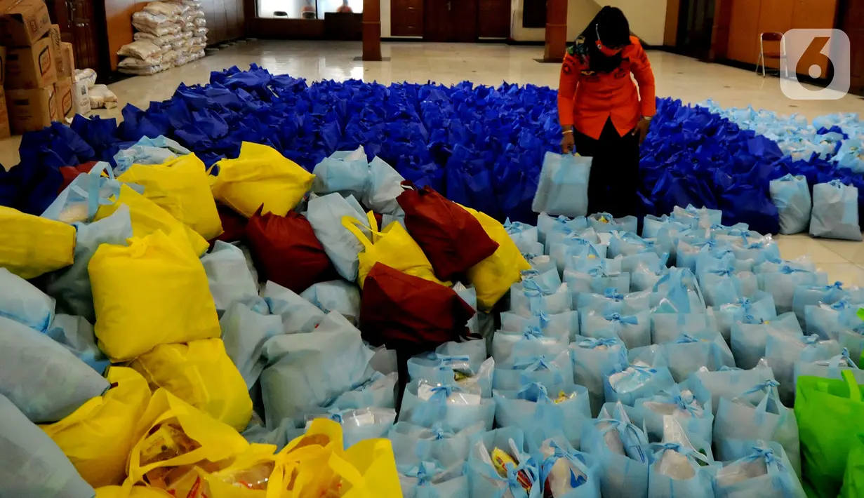 Petugas menata bansos berupa bahan pangan untuk didistribusikan kepada warga terpapar COVID-19 yang menjalani isolasi mandiri di rumah di Gedung Wanita, Kota Bogor, Jumat (9/7/2021). Setiap harinya, bonsos dibagikan kepada warga melalui keluarahan. (merdeka.com/Arie Basuki)