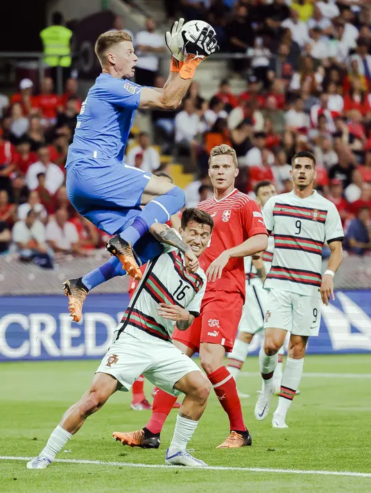 Penjaga gawang Swiss Jonas Omlin (kiri) melakukan penyelamatan terhadap pemain Portugal Otavio (tengah) pada pertandingan sepak bola Grup A2 UEFA Nations League di Stadion Stade de Geneve, Jenewa, Swiss, 12 Juni 2022. Portugal kalah tipis 0-1 dari Swiss. (Michael Buholzer/Keystone via AP)