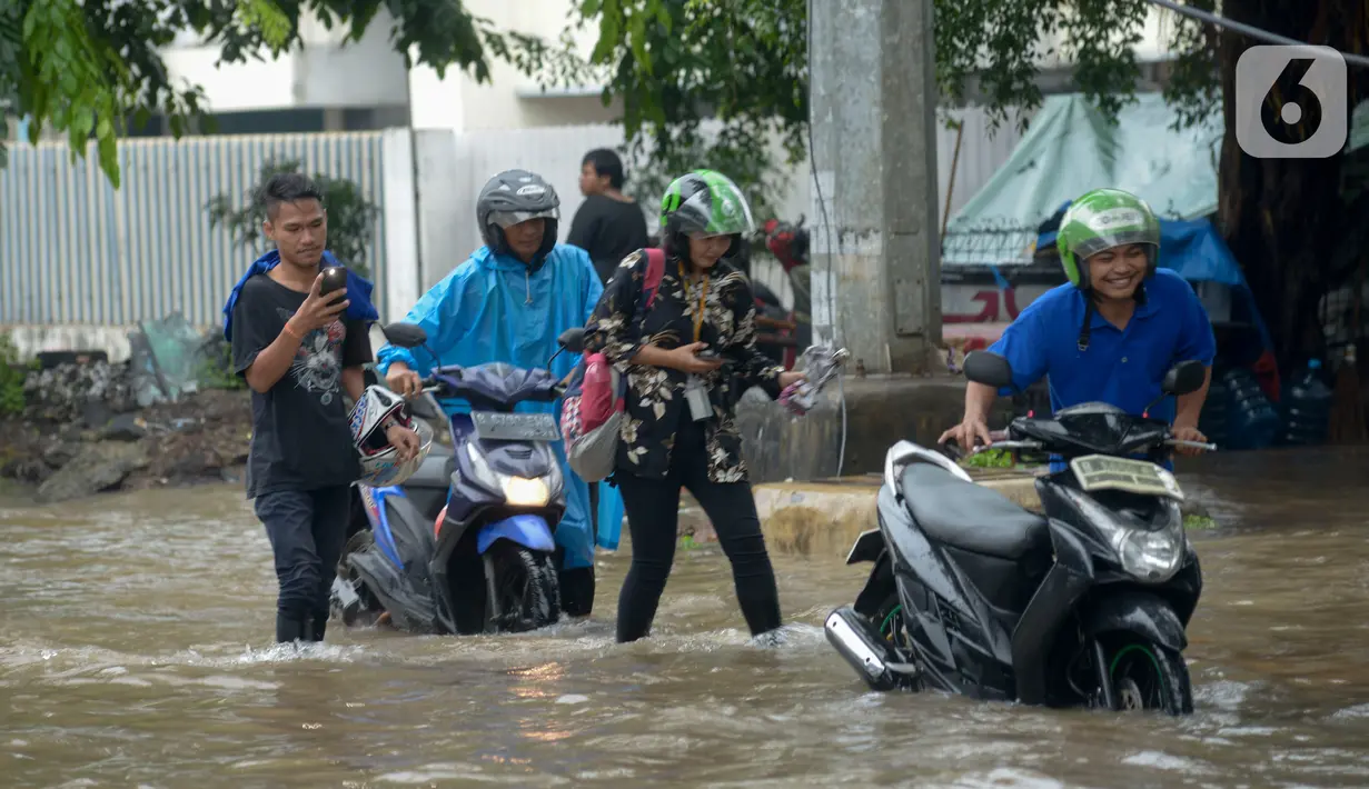 Pengendara mendorong sepeda motor mereka saat melewati banjir yang merendam Jalan Ahmad Yani, Jakarta, Sabtu (8/2/2020). Hujan yang mengguyur Jakarta sejak semalam membuat sejumlah ruas jalan terendam banjir. (merdeka.com/Imam Buhori)