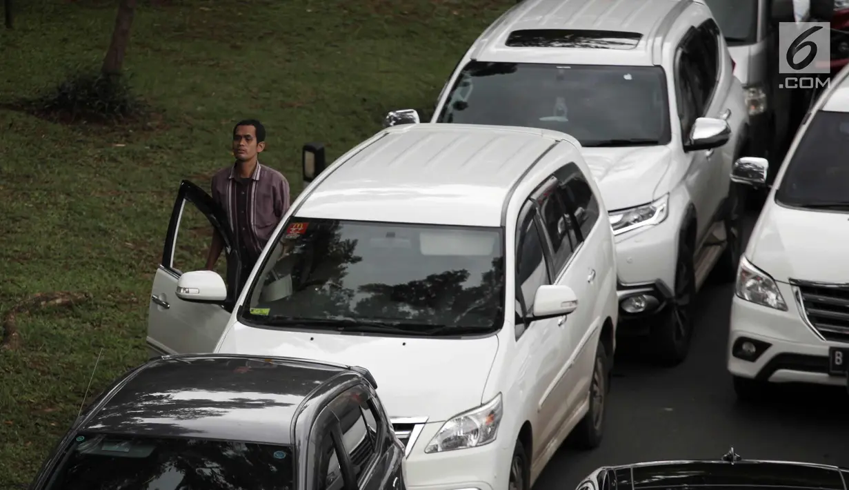 Seorang pengendara turun dari mobil saat kemacetan di Jalan KH Abdullah Syafei, Tebet, Jakarta, Senin (12/2). Kemacetan tersebut imbas dari demo sopir angkot Mikrolet 44 dan metro mini Dian Mitra. (Liputan6.com/Arya Manggala)