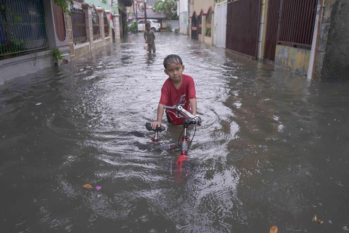 FOTO: Drainase Meluap, Warga Pasar Rebo Terobos Genangan