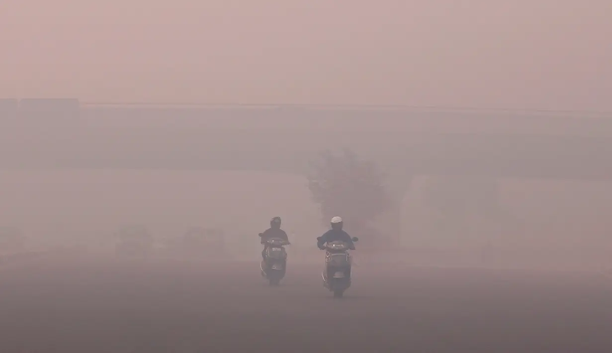 Pengendara motor berjalan di tengah kabut tebal akibat polusi setelah perayaan Diwali di New Delhi, India (31/10). Tingkat polusi ini mencapai hingga partikulat PM10 dan dianggap berbahaya bagi kesehatan. (Reuters/Adnan Abidi)