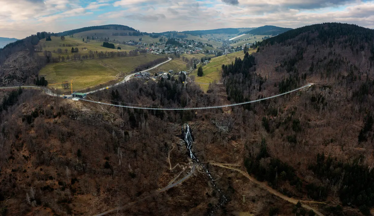 Foto udara yang diambil pada 3 Maret 2023 menunjukkan jembatan gantung yang sedang dibangun, menghadap ke air terjun di Todtnau, barat daya Jerman. Pembangunan jembatan sepanjang 450 meter yang digantung dengan ketinggian hingga 120 meter ini diharapkan selesai pada Mei 2023 dan menjadi daya tarik wisata utama di Black Forest. (PATRICK HERTZOG / AFP)