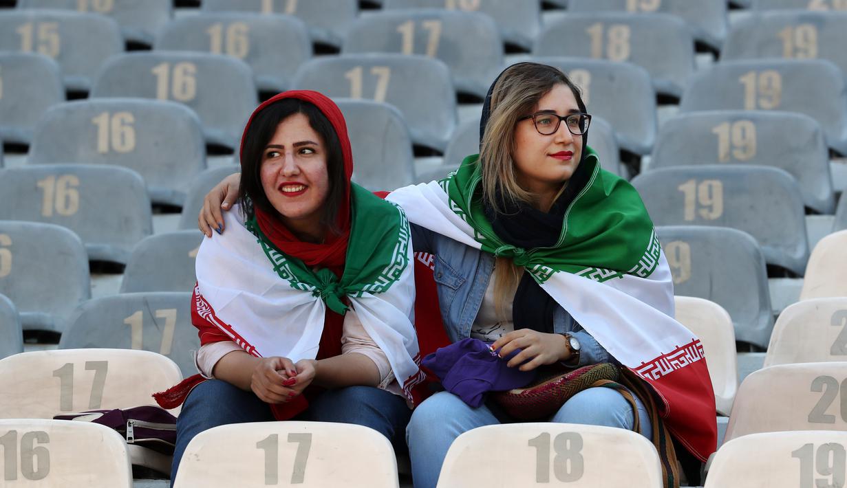 Wanita Iran mengenakan bendera negara mereka saat menyaksikan laga kualifikasi Piala Dunia 2022 antara Iran dengan Kamboja di Stadion Azadi, Teheran, Iran, Kamis (10/10/2019). Ini merupakan pertama kalinyqa wanita Iran boleh menonton bola dalam stadion sejak tahun 1981. (AP Photo/Vahid Salemi)