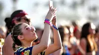 Seorang wanita mengambil gambar saat menghadiri Coachella Music & Arts Festival 2018 di Empire Polo Club di Indio, Calif (15/4). Festival ini selalu ditunggu oleh pencinta musik dunia dan selebriti Hollywood. (AFP Photo/Rich Fury)