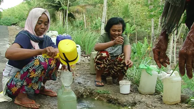 Warga mengambil aira dari bocoran pipa PDAM.