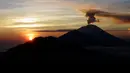 Gunung Agung mengembuskan asap saat matahari terbit (sunrise) terlihat dari Kintamani, Bali, Rabu (13/12). Visual Gunung Agung tampak cerah, asap yang keluar dari kawah gunung itu masih rutin keluar meski tidak secara menerus. (AP Photo/Firdia Lisnawati)