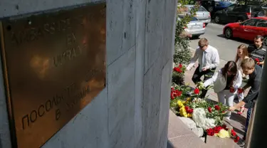 Sejumlah orang menaruh bunga di depan Kedutaan Besar Prancis di Kiev, Ukraina, (15/7). Karangan bunga tersebut untuk menghormati para korban teror Truk Maut saat perayaan hari Bastille di Nice. (REUTERS/Gleb Garanich)