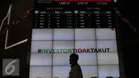 Pengunjung melintas di bawah layar bertuliskan #investor tidak takut di Bursa Efek Indonesia, Jakarta, Senin (18/1). (Liputan6.com/Angga Yuniar)