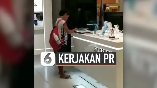 Seorang bocah mengerjakan tugas sekolahnya menggunakan perangkat display di gerai Samsung. Ini dilakukannya karena tak memiliki gadget dan juga internet.