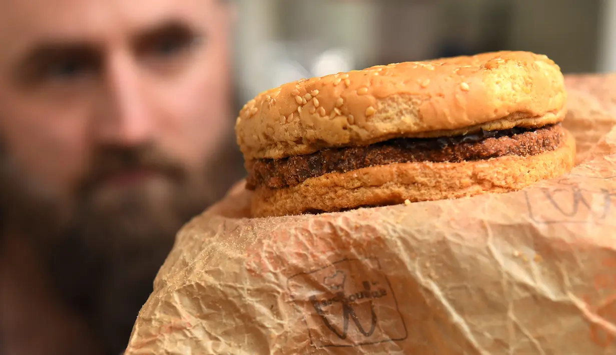 Casey Dean memeriksa burger McDonald's yang dibeli pada 1995 dan disimpan di gudang Australia selama bertahun-tahun, di Melbourne, 7 November 2019. Burger itu disimpan di dalam kotak terbuat dari kayu dan kardus dan ditutup menggunakan kunci di rumah Melbourne. (William WEST/AFP)