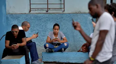 Orang-orang menggunakan ponsel mereka untuk terhubung ke internet melalui WiFi di sebuah taman di Havana, Rabu (5/12). Pemerintah Kuba mengumumkan bahwa masyarakat bisa mengakses internet secara bebas di ponsel mereka mulai Kamis ini. (YAMIL LAGE/AFP)